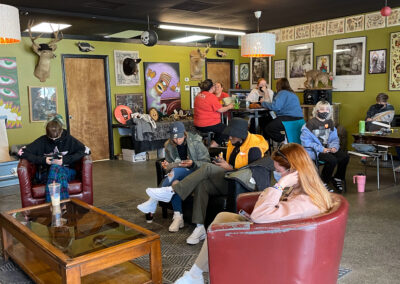 Waiting area at Glory Bound Tattoo. Ten individuals seated and standing around the room.