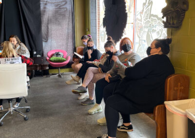 Waiting area at Glory Bound Tattoo. Eight individuals seated around the room.