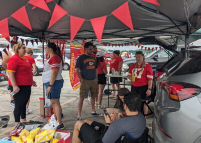 People standing, sitting, and talking at MOCSA's Chiefs tailgate party.