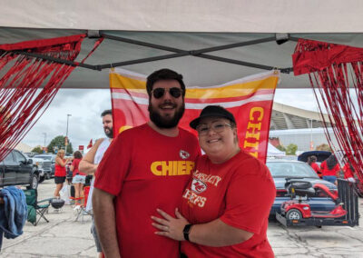 Two individuals at MOCSA's Chiefs tailgate party wearing red Chiefs t-shirts smiling at the camera.
