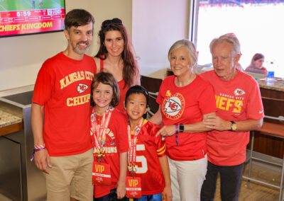 At Chiefs Charity Game, group picture of MOCSA supporters (four adults, two children) in suite.