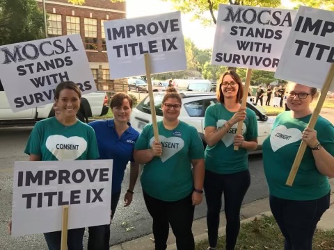 Victoria Pickering and MOCSA staff holding signs that say "improve title IX" and "MOCSA stands with survivors"