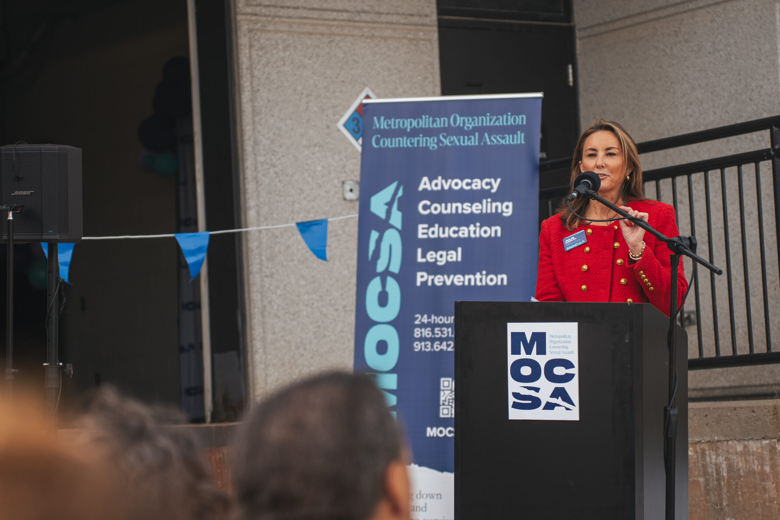 Julie Donelon, MOCSA President & CEO, stands behind a podium during MOCSA Groundbreaking