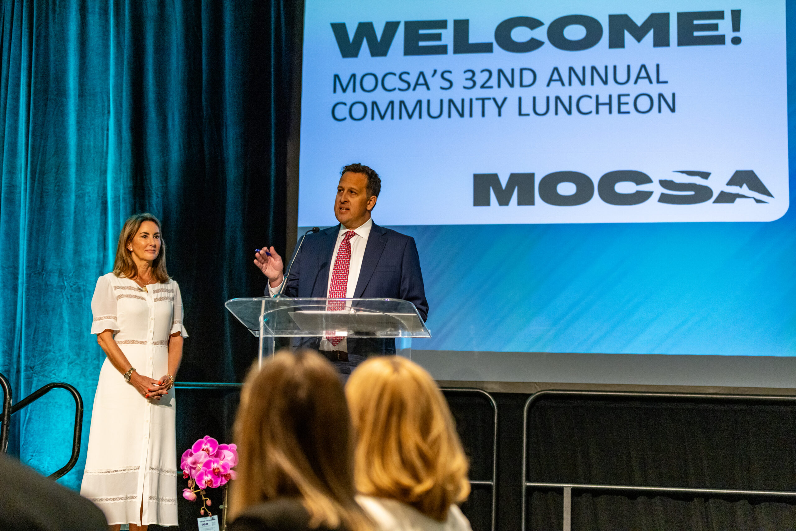 Julie Donelon, MOCSA President & CEO and Zach Bickel, MOCSA 2026 Board Chair stand behind an acrylic podium on stage