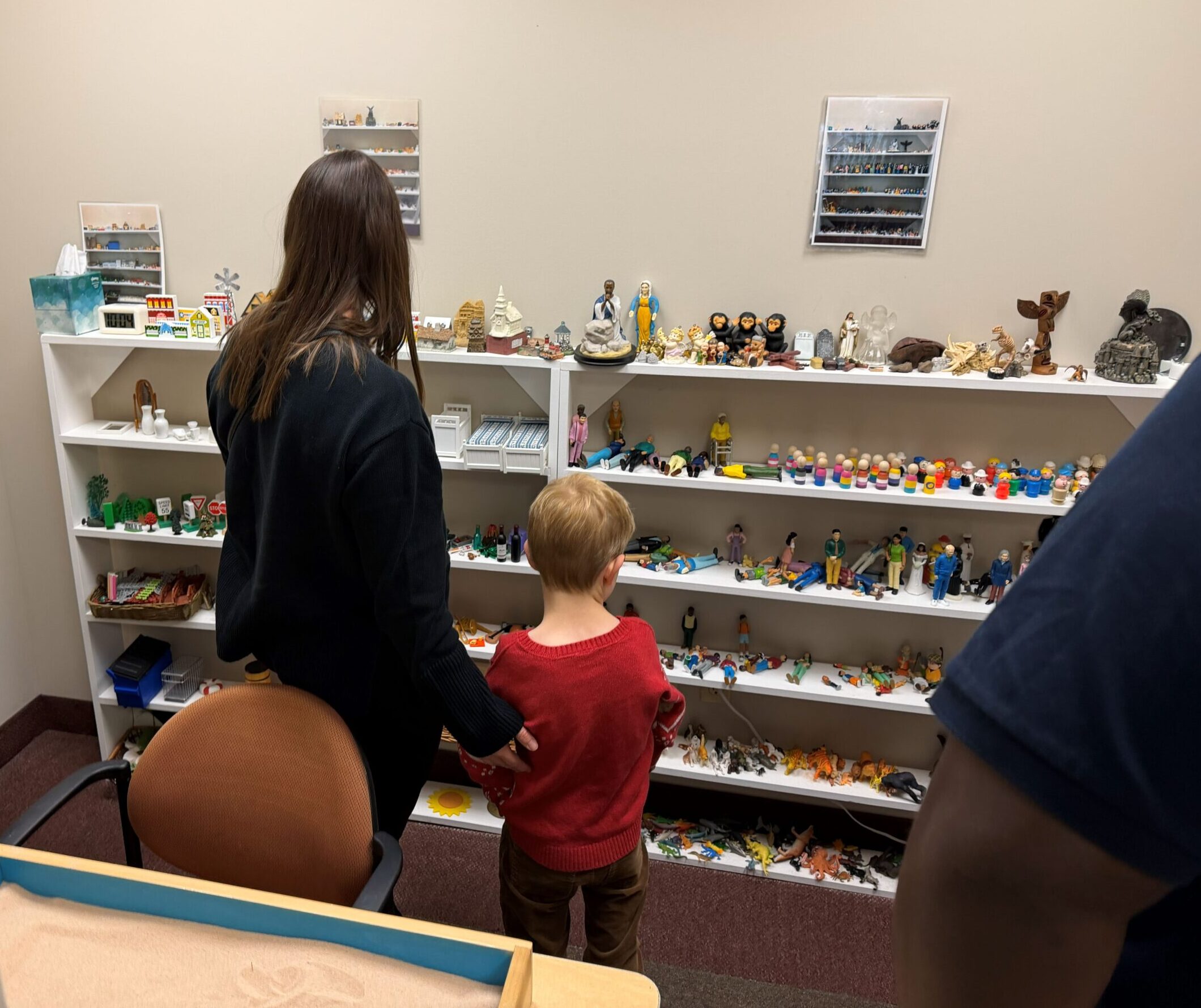 Sand Tray Therapy Room Woman and Child look at toys available to use when interacting with sand tray therapy