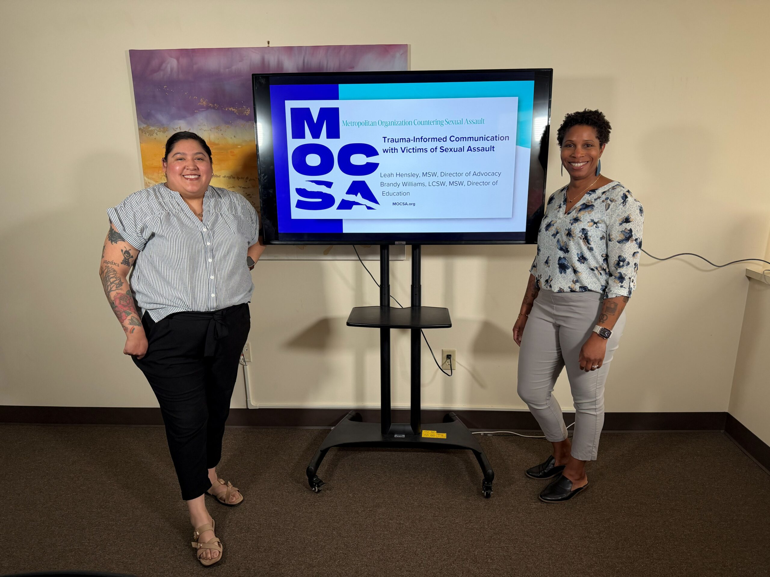 Leah and Brandy Presentation Two presenters stand beside a projection of a MOCSA presentation